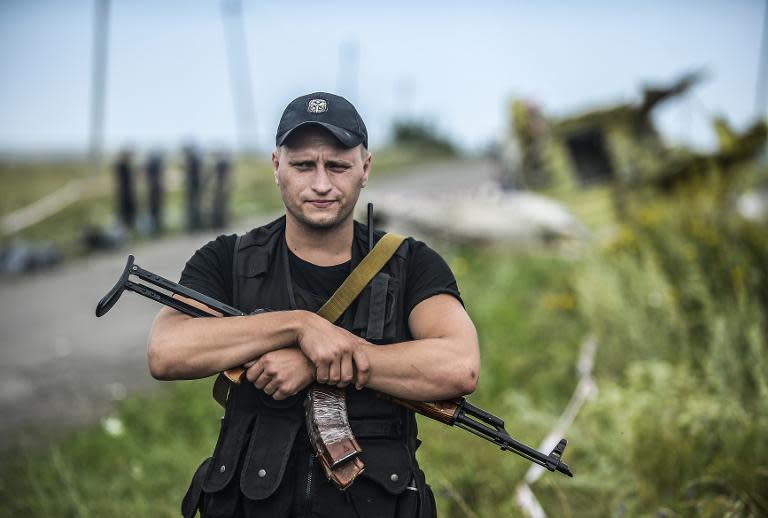 An armed pro-Russian separatist stands guard near a piece of the wreckage of the Malaysia Airlines Flight MH17, near the village of Grabove, in the region of Donetsk on July 20, 2014