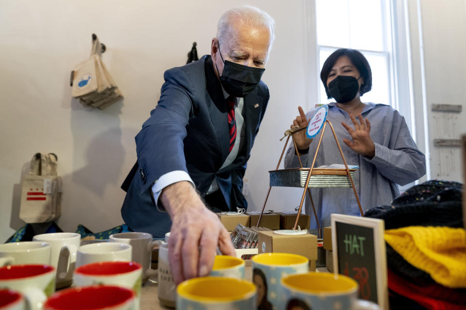 Owner Viboonrattana "Moo" Honey watches as President Joe Biden picks up a Vice President Kamala Harris mug as he visits the Honey Made store in Washington, Tuesday, Jan. 25, 2022. (AP Photo/Andrew Harnik)