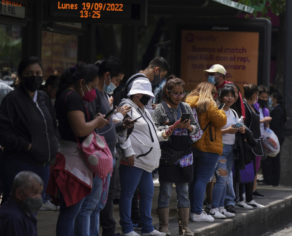 People gather outside at a bus stop after a magnitude 7.6 earthquake was felt in Mexico City, Monday, Sept. 19, 2022. There were no immediate reports of damage from the quake that hit at 1:05 p.m. local time, according to the U.S. Geologic Survey, which said the quake was centered near the boundary of Colima and Michoacan states. (AP Photo/Fernando Llano)