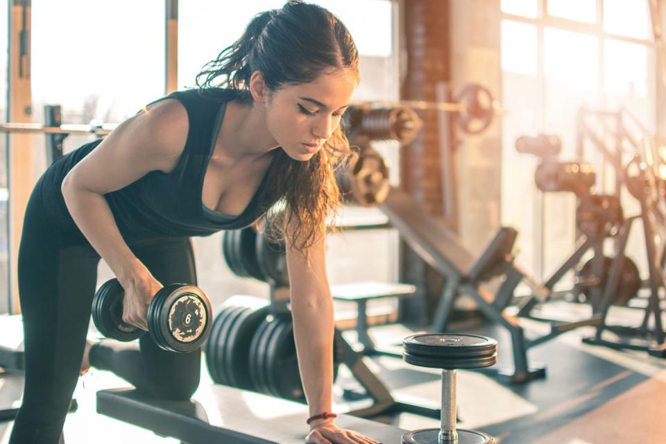 slim sporty woman working out with dumbbell in the gym