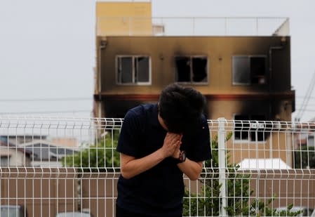 A man prays for victims in front of the torched Kyoto Animation building in Kyoto