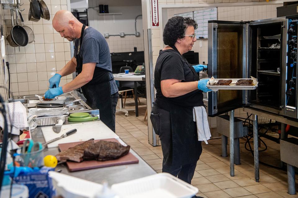 Chef Ben Malone and Lisa Franco, cook and catering and barbecue manager, prepare to-go orders at Smoked! BBQ in West Asheville, October 4, 2023.