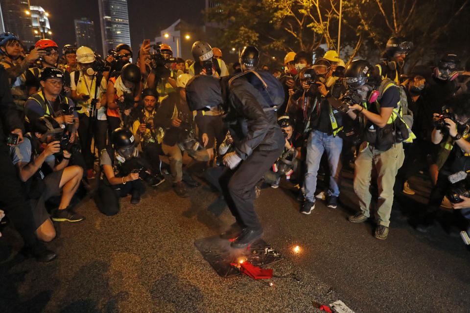 A black-clad protester wearing goggles and a mask stomps on a burning Chinese flag in Hong Kong, Saturday, Sept. 28, 2019. The protestors attempted to scale barricades outside the government offices, prompting riot police behind the barriers to fire pepper spray. The protesters retreated but returned, heckling police and thumping metal fencing. Police used pepper spray again, and the scene repeated several times. Some journalists were hit by the spray. (AP Photo/Vincent Thian)
