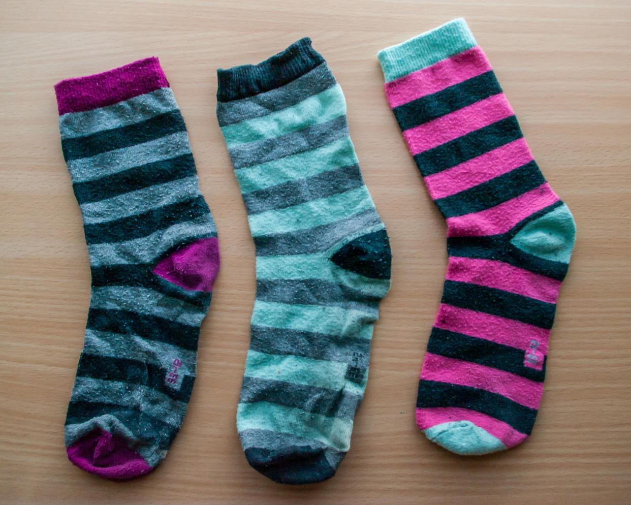 three mismatched socks on a wooden surface