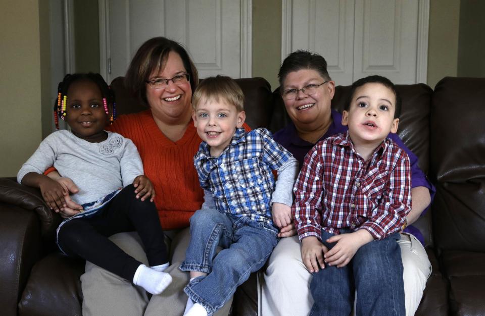 FILE - In this March 5, 2013, file photo, April DeBoer, second from left, sits with her adopted daughter Ryanne, 3, left, and Jayne Rowse, fourth from left, and her adopted sons Jacob, 3, middle, and Nolan, 4, right, at their home in Hazel Park, Mich. A federal judge has struck down Michigan's ban on gay marriage, Friday, March 21, 2014, the latest in a series of decisions overturning similar laws across the U.S. The two nurses who've been partners for eight years claimed the ban violated their rights under the U.S. Constitution. (AP Photo/Paul Sancya, File)