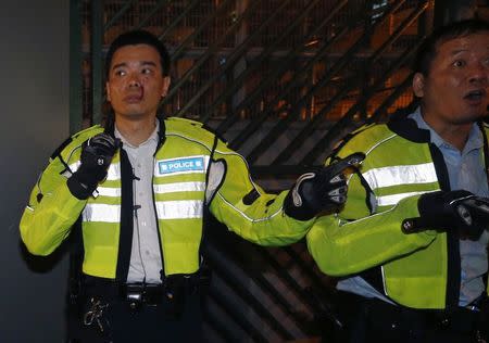 A policeman (L), with blood from wounds on his face, carries a baton next to another officer during a confrontation with protesters trying to block a side street at Mongkok shopping district in Hong Kong early November 29, 2014. REUTERS/Bobby Yip