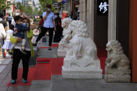 A woman carries a child near stone lions on the popular Wangfujing shopping district in Beijing Tuesday, May 11, 2021. The number of working-age people in China fell over the past decade as its aging population barely grew, a census showed Tuesday, adding to economic challenges for Chinese leaders who have ambitious strategic goals. (AP Photo/Ng Han Guan)