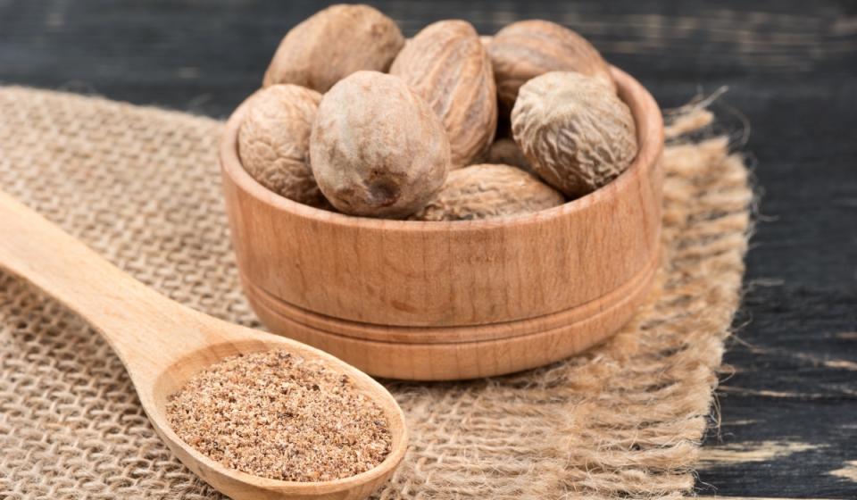 Whole and ground nutmegs in a bowl for the holidays