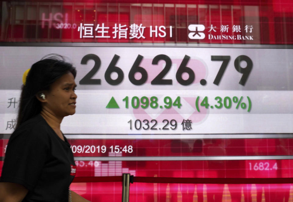 A woman walks past an electronic board showing Hong Kong share index outside a local bank in Hong Kong, Wednesday, Sept. 4, 2019. Asian stock markets rose Wednesday following surprise weakness in U.S. manufacturing and wrangling in Britain over the country's departure from the European Union. (AP Photo/Vincent Yu)