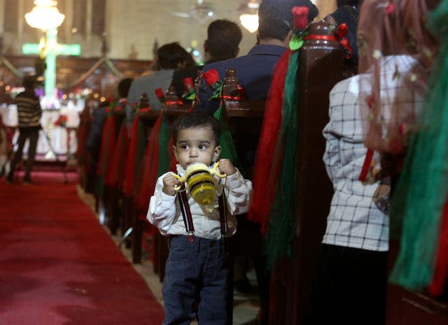 A Christian child stands beside his mother attending midnight Christmas mass at St. Andrews Church, in Karachi, Pakistan (Fareed Khan/AP)