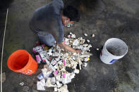 West Street Recovery's Martin Uribe sorts through plumbing repair pieces as he works to repair busted pipes that were frozen during a recent winter storm, Thursday, Feb. 25, 2021, in Houston. West Street Recovery, a nonprofit created in the wake of Hurricane Harvey to help repair flood damaged homes, has been working since the winter storm hit to repair and replace damaged plumbing systems for residents who can't afford to do so. (AP Photo/David J. Phillip)