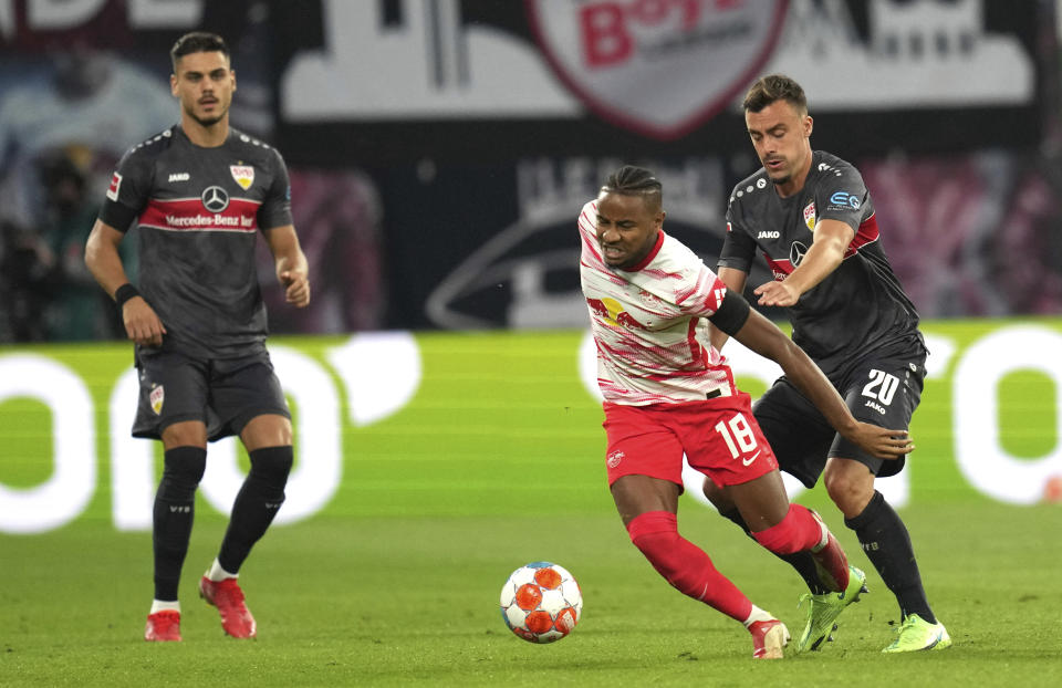 Leipzig's Christopher Nkunku, center, is challenged for the ball by Stuttgart's Philipp Foerster, right, during the German Bundesliga soccer match between RB Leipzig and VfB Stuttgart in Leipzig, Germany, Friday, Aug. 20, 2021. (AP Photo/Michael Sohn)