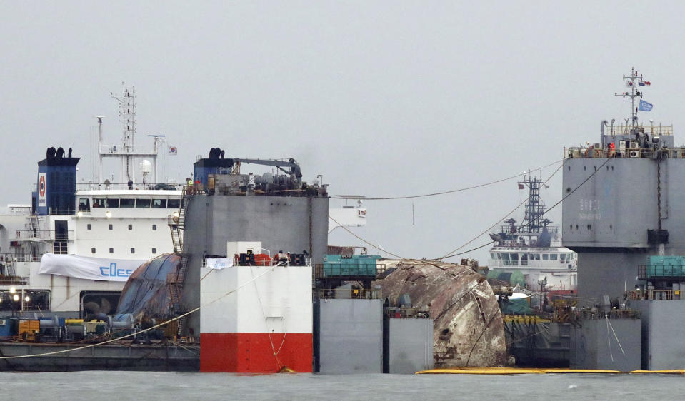 The sunken Sewol ferry is loaded onto a semi-submersible transport vessel during the salvage operation in waters off Jindo, South Korea, Saturday, March 25, 2017. Salvage crews towed the corroded 6,800-ton South Korean ferry toward a transport vessel on Friday after it was successfully raised from waters off the country's southwest coast. The massive attempt to bring the ferry back to shore, nearly three years after it sank, killing 304 people, is being closely watched by a nation that still vividly remembers the horrific accident. (Lee Jin-wook/Yonhap via AP)