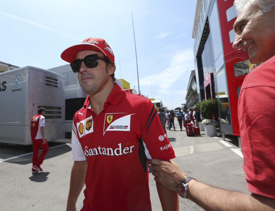 Ferrari driver Fernando Alonso of Spain, left, is welcomed by Italian photographer Filippo Di Mario as he walks in the paddock upon his arrival at the Catalunya racetrack in Montmelo, near Barcelona, Spain, Thursday, May 8, 2014. Fernando Alonso proved last season that wise tire management and smooth pit stops can be enough to compensate for a lack of overall speed. Alonso enters the race in a distant third place, with 41 points to Rosberg's 79 and Hamilton's 75, but after managing to finally reach the podium at Shanghai in Ferrari's first race under new team principal Marco Mattiacci. The Formula One race will be held on Sunday. (AP Photo/Luca Bruno)