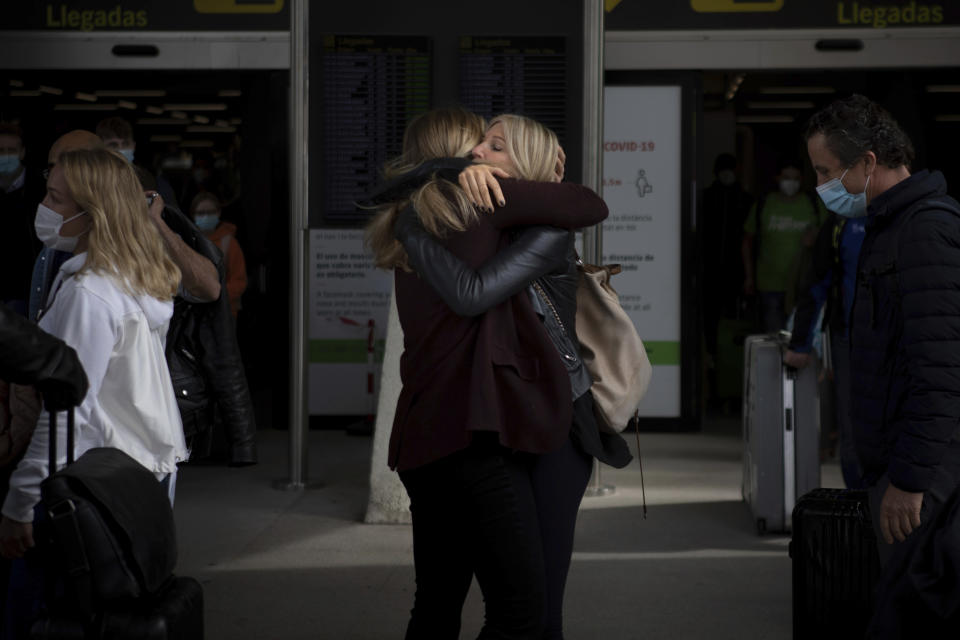 Two women meet at Palma de Mallorca Airport on the Spanish Balearic Island of Mallorca, Spain, Saturday, March 27, 2021. Efforts in Spain to restart tourism activity is drawing a mixed picture due to a patchwork of national, regional and European rules on travel that is confusing both tourists and their hosts. (AP Photo/Francisco Ubilla)