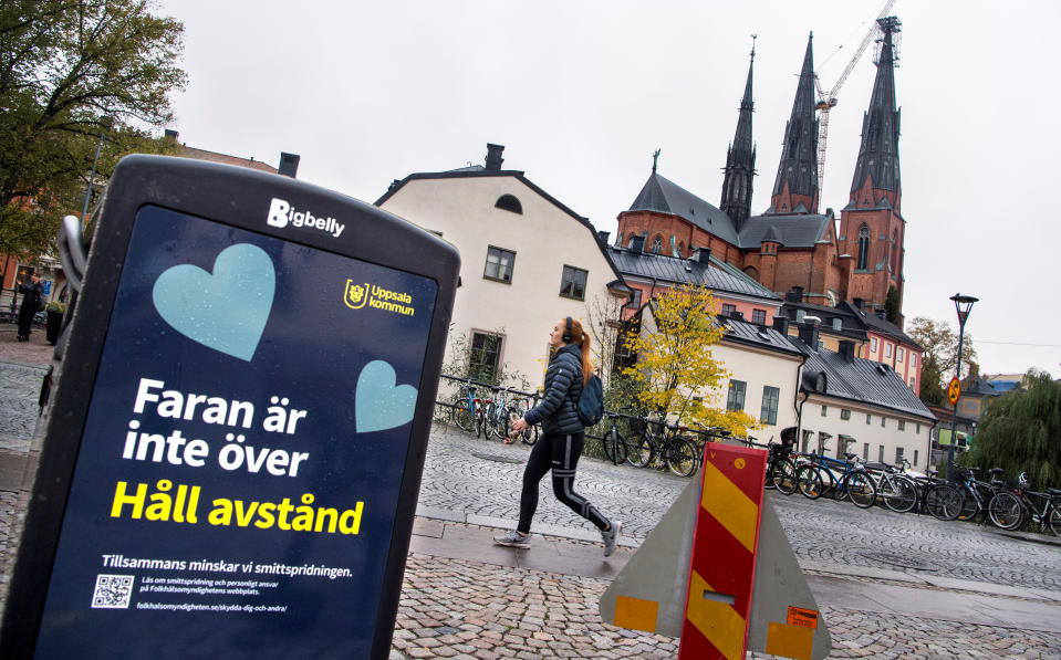 A woman walks near a trash can with a sign reading "The danger is not over - Keep your distance" on a pedestrian street as the coronavirus disease (COVID-19) outbreak continues in Uppsala, Sweden October 21, 2020. TT News Agency/Claudio Bresciani via REUTERS      ATTENTION EDITORS - THIS IMAGE WAS PROVIDED BY A THIRD PARTY. SWEDEN OUT.