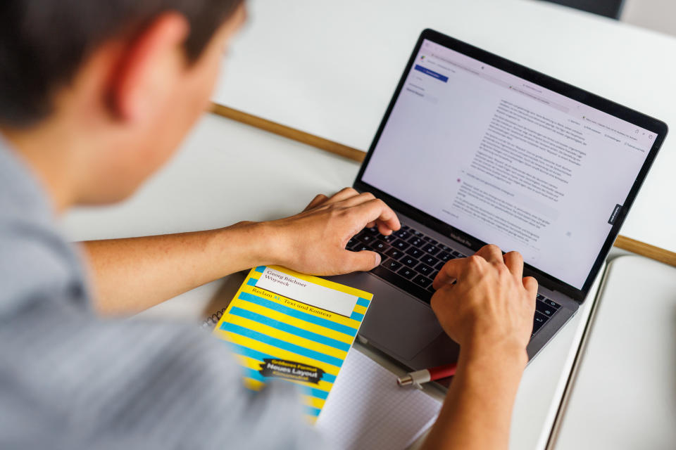 A student types on a laptop while using an AI tool.