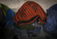 A migrant looks out from his tent while bracing against harsh winter weather inside an abandoned hangar near the Hungarian border, outside of the village of Majdan, Serbia, Tuesday, Jan. 11, 2022. Hungary's nationalist prime minister, Viktor Orban, is keen to use the threat of migrants at his country's southern border to give him an advantage in upcoming elections. But the scale of migration pressure claimed by Orban is drawn into question by statistics from neighboring Serbia and the European Union's border agency. (AP Photo/Bela Szandelszky)