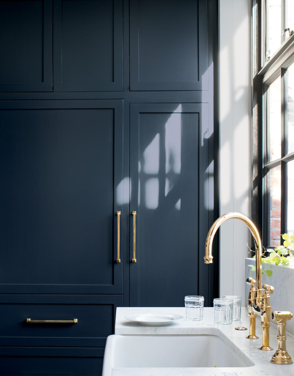 Kitchen with tall blue painted cabinets, sink and faucet and white countertop