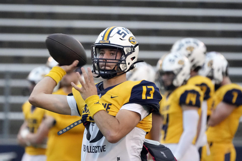 Saline High School quarterback CJ Carr (13) warms up before a football game Friday, Oct. 27, 2023, in Saline, Mich. Carr will be among the hundreds of football players to sign a national letter of intent this week, sealing his commitment to join Notre Dame, but no one has a story quite the same. (AP Photo/Carlos Osorio)