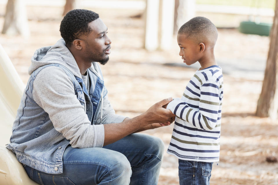 Adult and child having a conversation, adult is crouching to be at eye level with the child