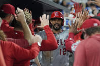 Los Angeles Angels teammates congratulate Aaron Hicks (12) after he scored during the sixth inning of a baseball game against the Miami Marlins, Tuesday, April 2, 2024, in Miami. (AP Photo/Marta Lavandier)