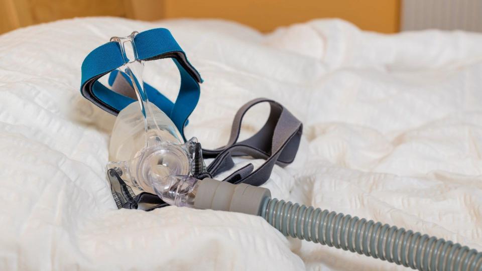 CPAP or APAP machine with mask and hose for people with sleep apnea on a pillow.