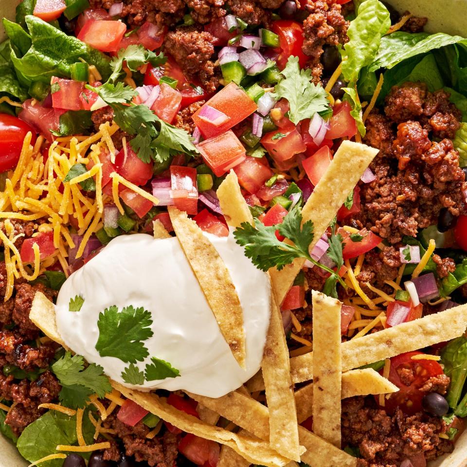 taco salad with sour cream, tomatoes, ground beef, and tortilla strips