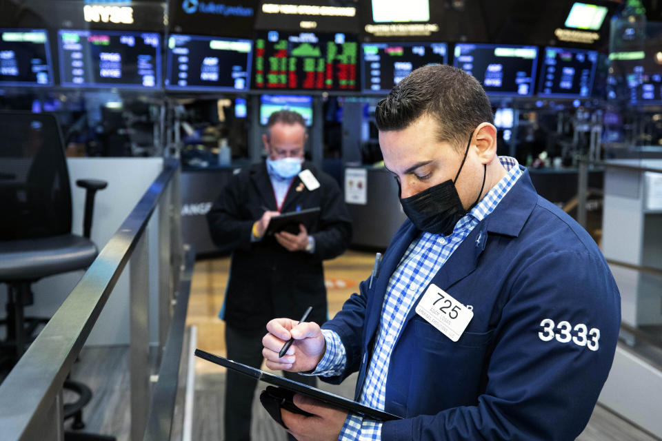 In this photo provided by the New York Stock Exchange, Adam Logan, foreground, works with a fellow trader on the floor, Friday, April 9, 2021. Technology companies helped lift stocks higher on Wall Street in afternoon trading Friday, placing the market within striking distance of more record highs. (Colin Ziemer/New York Stock Exchange via AP)