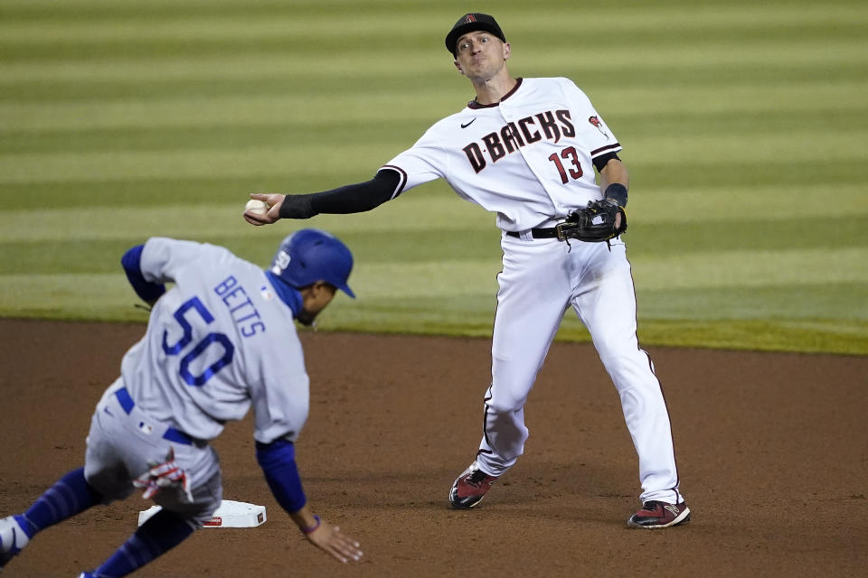 Arizona Diamondbacks' Nick Ahmed (13) forces out Los Angeles Dodgers' Mookie Betts (50) as he turns a double play on Corey Seager during the fourth inning of a baseball game, Thursday, Sept. 10, 2020, in Phoenix. (AP Photo/Matt York)