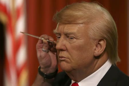 A gallery assistants poses, pretending to put the finishing touches to the hair and make-up of a waxwork of U.S. President-elect Donald Trump, during a media event at Madame Tussauds in London, Britain January 18, 2017. REUTERS/Neil Hall