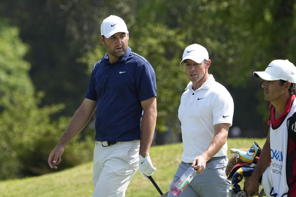 Scottie Scheffler, left, and Rory McIlroy, of Northern Ireland, center, walk up the fairway on the fifth hole during a consolation match at the Dell Technologies Match Play Championship golf tournament in Austin, Texas, Sunday, March 26, 2023. (AP Photo/Eric Gay)