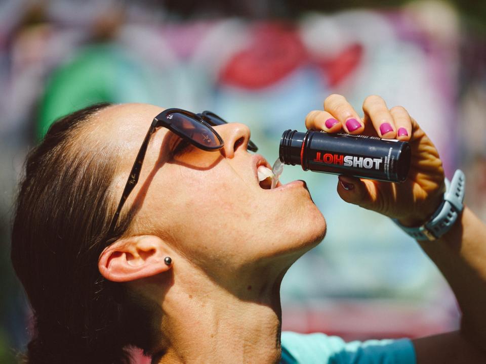 A woman pours HotShot into her mouth.