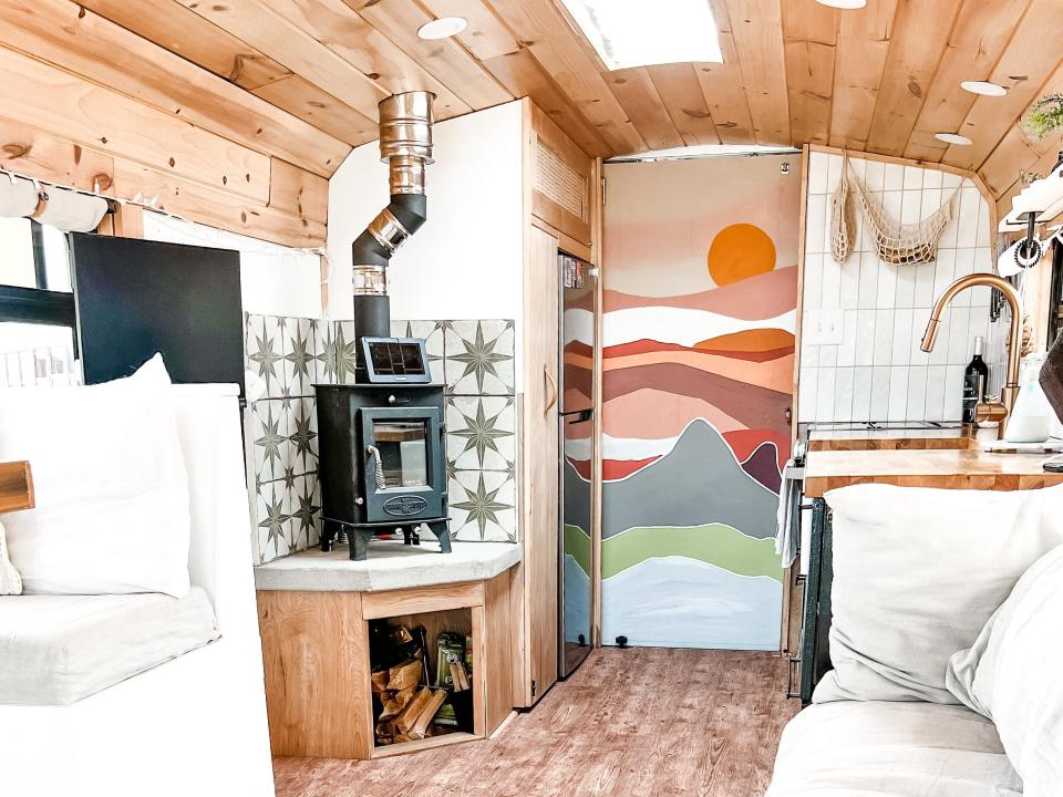 the inside of kristin reid's converted school bus, a couch on the right with a fire place to the left