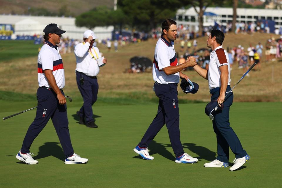 Viktor Hovland aperta a mão de Scottie Scheffler enquanto Brooks Koepka observa (REUTERS)