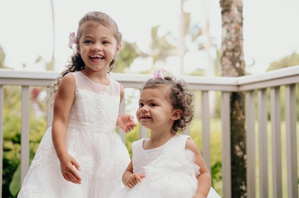 Both beaming flower girls <a href="https://www.instagram.com/p/B1p6lNGpbjO/" rel="nofollow noopener" target="_blank" data-ylk="slk:wore white gowns of their own;elm:context_link;itc:0;sec:content-canvas" class="link ">wore white gowns of their own</a>, with their hair pinned back and accented with pink flowers, for the beautiful day.