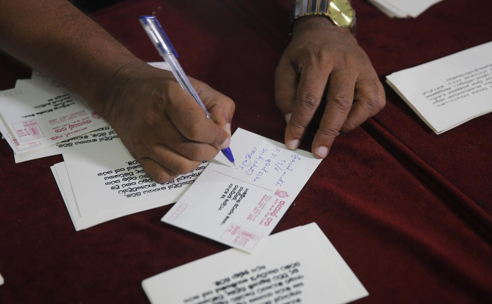 FILE- In this Jan. 24, 2017 file photo, a Sri Lankan media rights activist signs a postcard addressed to president Maithripala Sirisena during a petition signing demanding that Sirisena appoint a presidential commission to investigate all abductions during the country's brutal, decades-long civil war, in Colombo, Sri Lanka. Forced to flee their country a decade ago to escape allegedly state-sponsored killer squads, Sri Lankan journalists living in exile doubt they’ll be able to return home soon or see justice served to their tormentors _ whose alleged ringleader could come to power in this weekend’s presidential election. Exiled journalists and media rights groups are expressing disappointment over the current government’s failure in punishing the culprits responsible for crimes committed against media members. (AP Photo/Eranga Jayawardena, File)