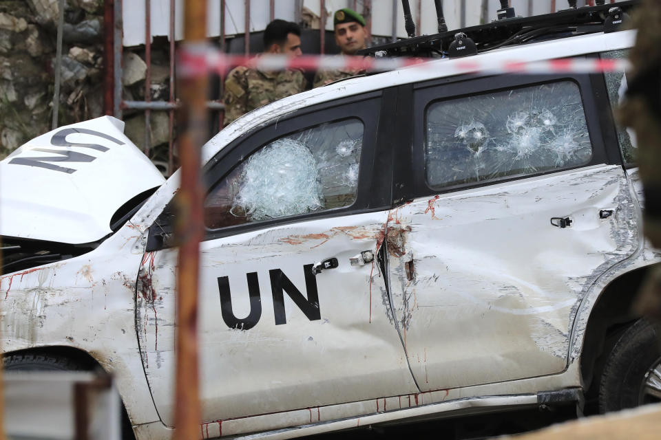 Lebanese soldiers stand behind a damaged UN peacekeeper vehicle at the scene where a UN peacekeeper convoy came under gunfire in the Al-Aqbiya village, south Lebanon, Thursday, Dec. 15, 2022. (AP Photo/Mohammed Zaatari)