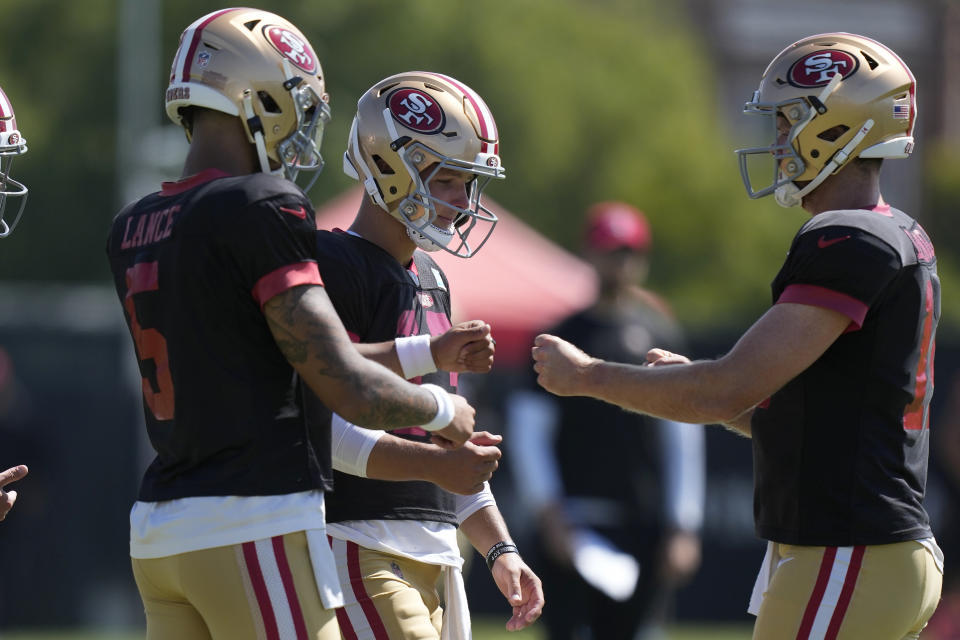 San Francisco 49ers quarterbacks Trey Lance, left, Brock Purdy, middle, and Sam Darnold gather during the NFL team's football training camp in Santa Clara, Calif., Tuesday, Aug. 1, 2023. (AP Photo/Jeff Chiu)