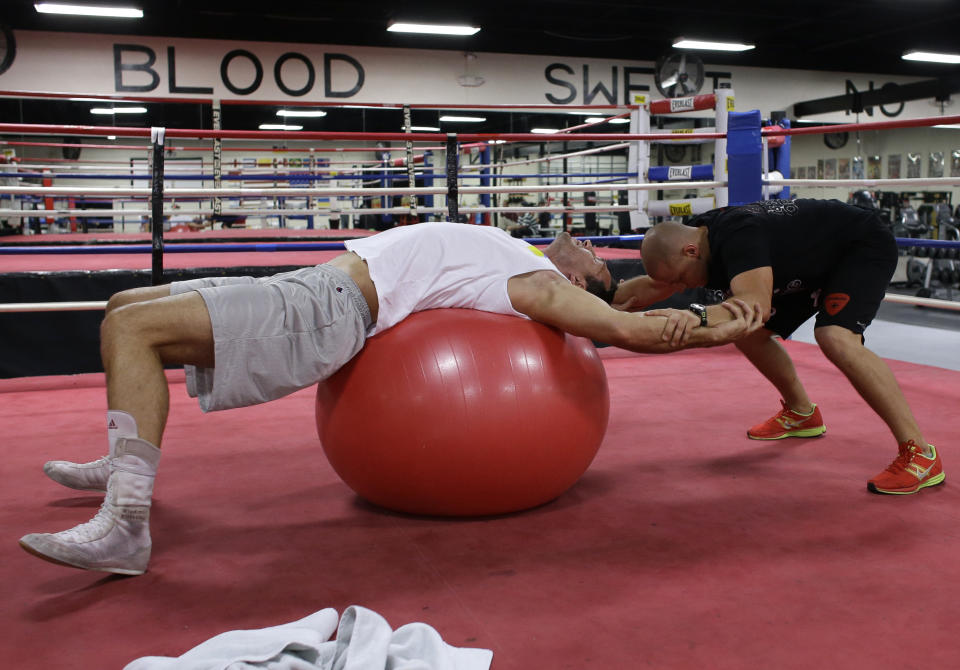 Undefeated heavyweight boxing champion Wladimir Klitschko, of Ukraine, left, stretches with his physical therapist Aldo Vetere, right, while training at the Lucky Street Boxing Gym, Thursday, March 20, 2014, in Hollywood, Fla. Klitschko is preparing for his upcoming fight in April against Alex Leapai in Germany. (AP Photo/Lynne Sladky)