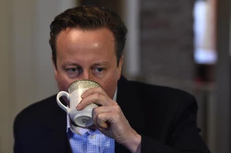 Britain's Prime Minister David Cameron enjoys a hot drink while he visits local members of the farming community during a campaign visit at Whole House Farm, near Brecon in Wales, Britain, May 6, 2015. REUTERS/Toby Melville