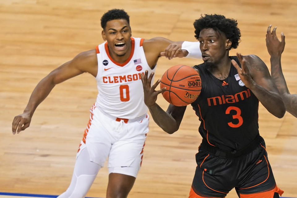 Miami center Nysier Brooks (3) tries to corral a rebound in front of Clemson guard Clyde Trapp (0) during the second half of an NCAA college basketball game in the second round of the Atlantic Coast Conference tournament in Greensboro, N.C., Wednesday, March 10, 2021. (AP Photo/Gerry Broome)