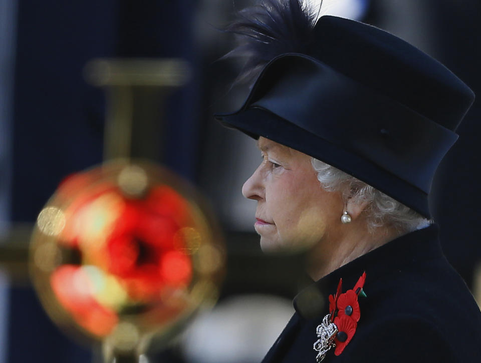FILE - Britain's Queen Elizabeth II stands by a cross bearing a poppy during the service of remembrance at the Cenotaph in Whitehall, London, Sunday, Nov. 11, 2012. Queen Elizabeth II will mark 70 years on the throne Sunday, Feb. 6, 2022 an unprecedented reign that has made her a symbol of stability as the United Kingdom navigated an age of uncertainty. (AP Photo/Kirsty Wigglesworth, File)