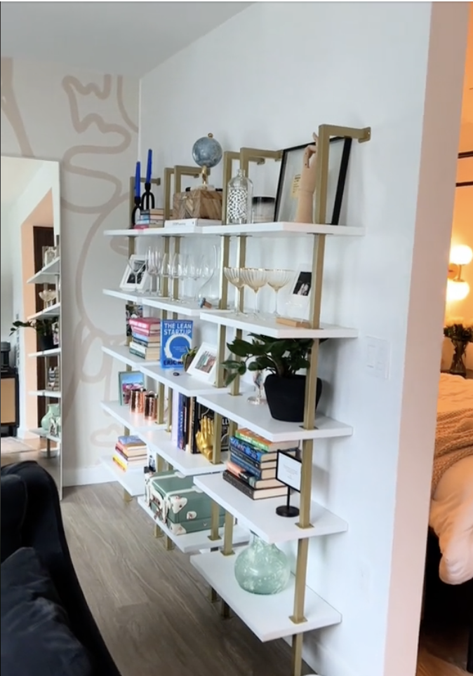 A well-organized living room shelving unit displaying books, decorative items, and glassware