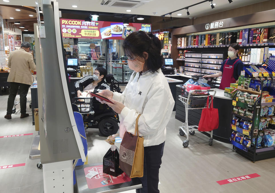 People wear face masks as they shop at a supermarket in Taipei, Taiwan, Monday, Feb. 20, 2023. Three years into the global pandemic, Taiwan said Monday, that people no longer have to wear masks at all times indoors though it is still keeping some restrictions in place. (AP Photo/Chiang Ying-ying)