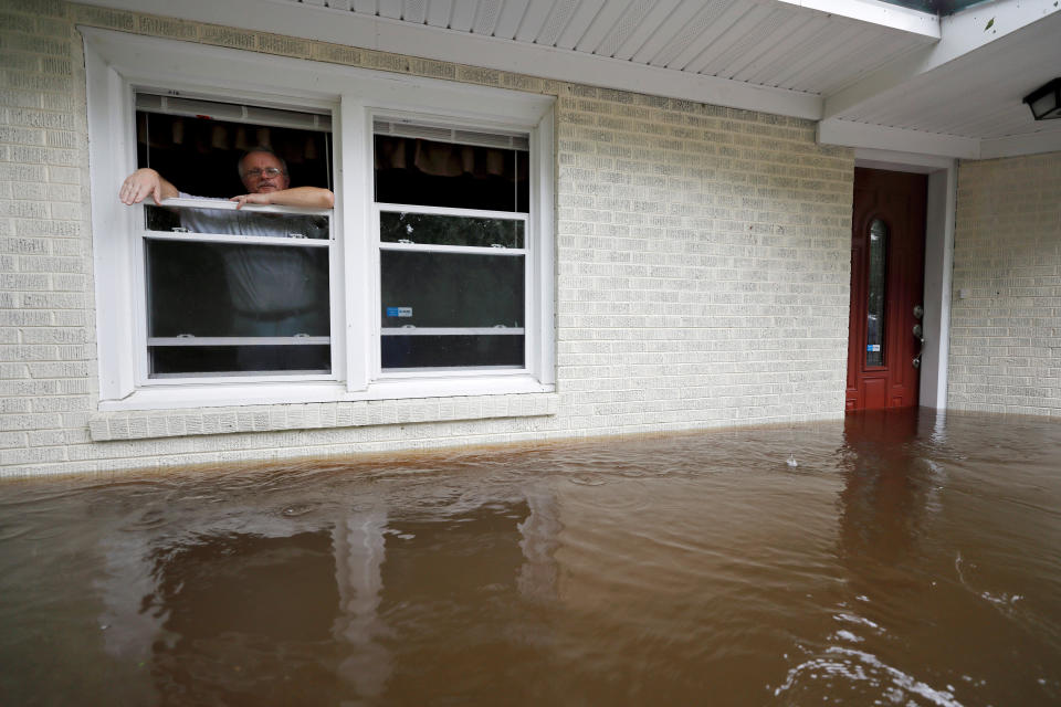 Obrad Gavrilovic peers out the window of his flooded home while considering whether to leave with his wife and pets, as waters rise in Bolivia, North Carolina.