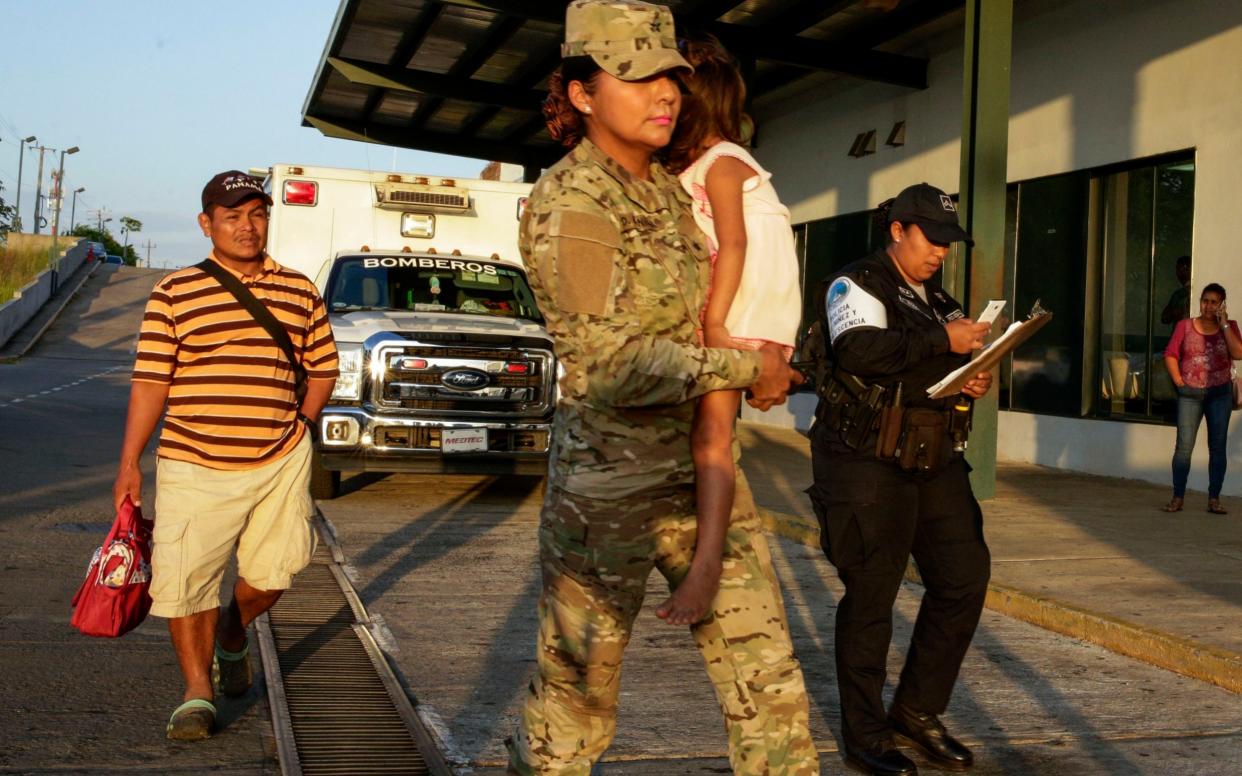 Jose Gonzalez, left, and his daughter, 5, carried by a police officer. Mr Gonzalez's wife and five of their children were killed - AP