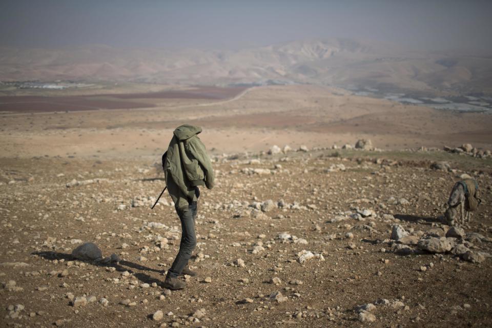 A young Palestinian shepherd lights a cigaret near the settlement of Mehola in the Jordan Valley, a strip of West Bank land along the border with Jordan, Thursday, Jan. 2, 2014. A senior Israeli Cabinet minister and more than a dozen hawkish legislators poured cement at a construction site in a settlement in the West Bank's Jordan Valley on Thursday, in what they said was a message to visiting U.S. Secretary of State John Kerry that Israel will never relinquish the strategic area. (AP Photo/Oded Balilty)