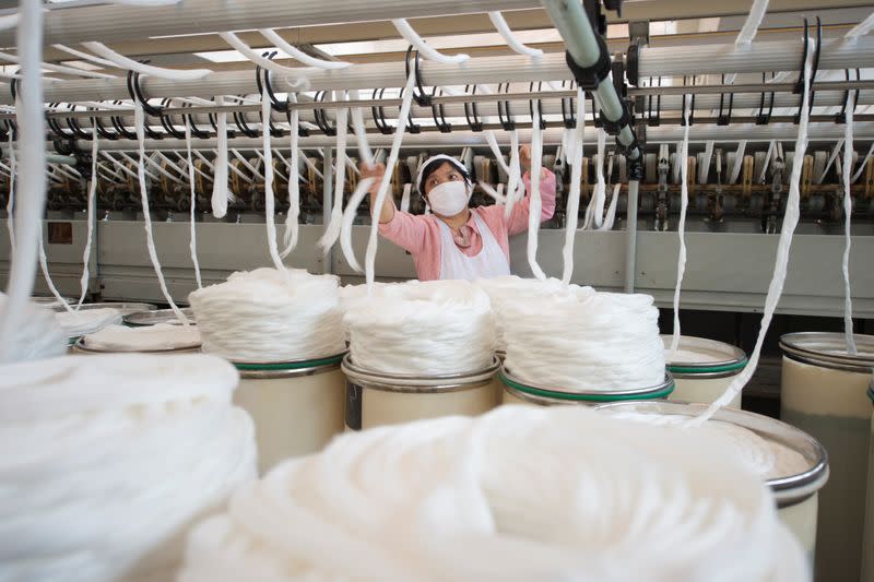 Employee wearing a face mask works on the production line at a textile factory in Haian