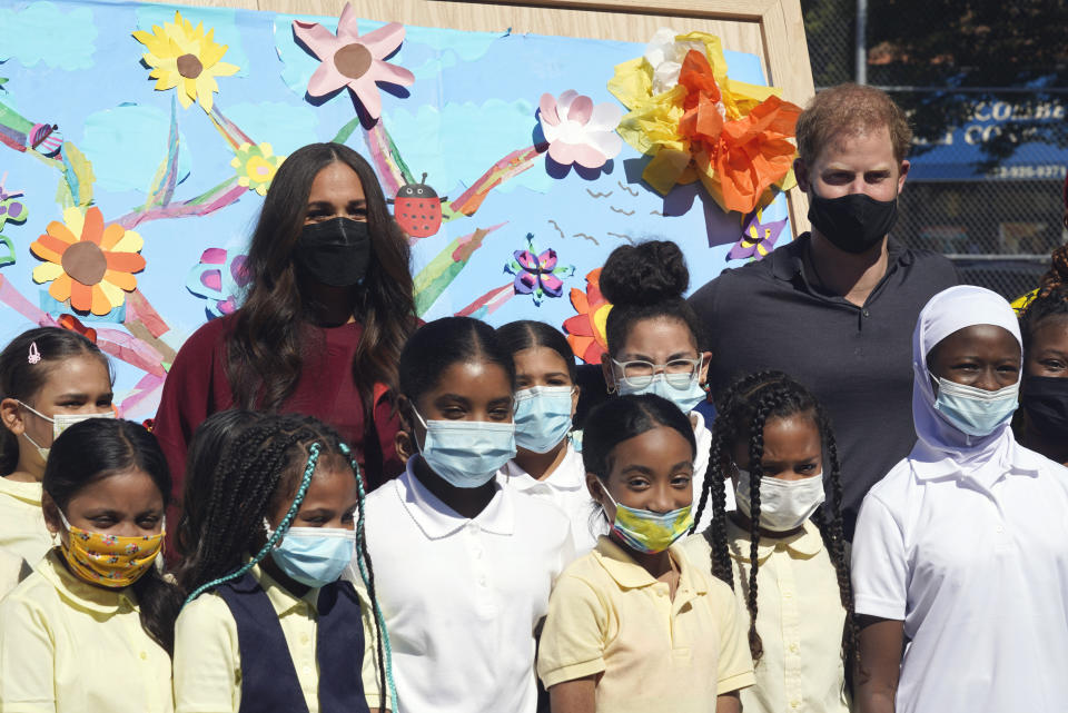 Prince Harry and Meghan, the Duke and Duchess of Sussex, pose for photos with a group of third grade students during their visit to P.S. 123, the Mahalia Jackson School, in New York's Harlem neighborhood, Friday, Sept. 24, 2021. (AP Photo/Richard Drew)